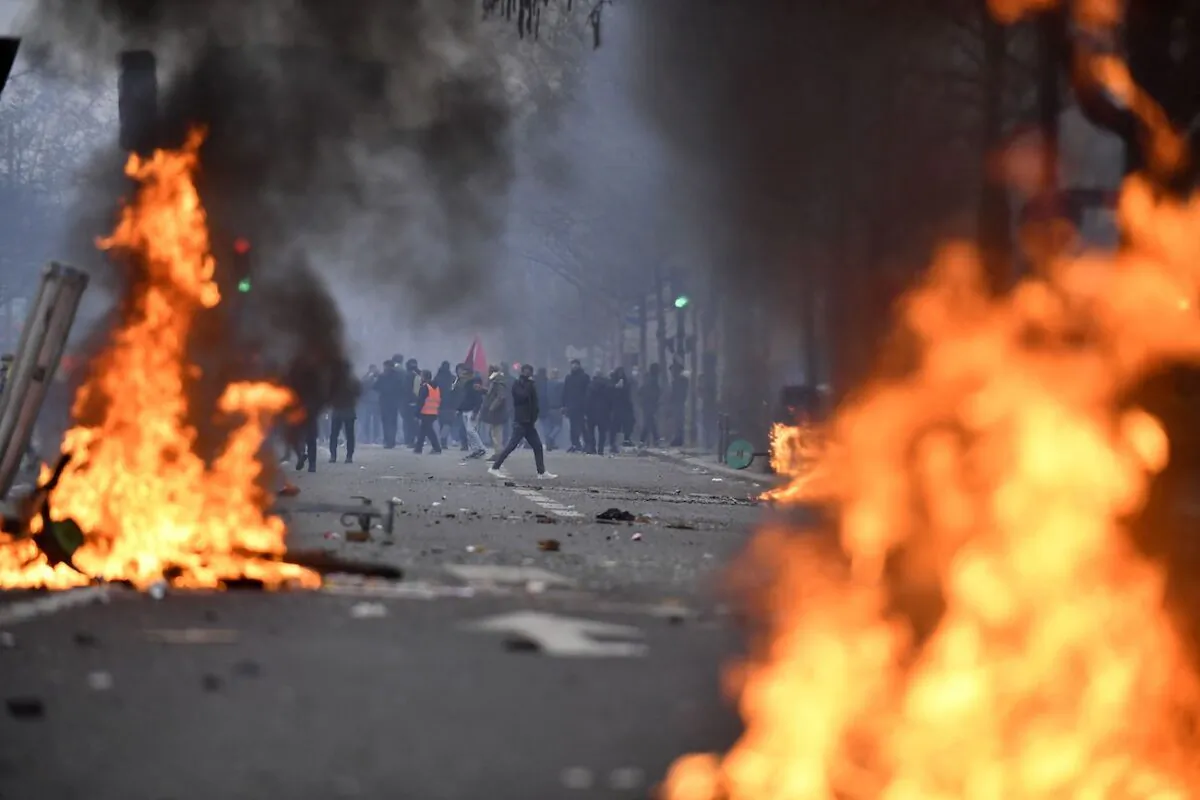 Protesters stand behind flames during clashes following a demonstration of members of the Kurdish community, a day after a gunman opened fire at a Kurdish cultural centre killing three people, at The Place de la Republique in Paris on Dec. 24, 2022. (Julien de Rosa/AFP via Getty Images)