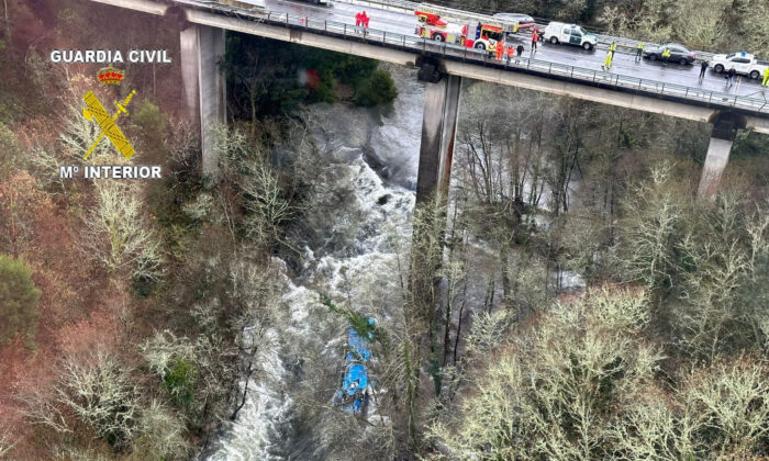 Paramedics work at the site of an accident where a passenger bus fell off a bridge into the Leres River in Serdedo Cotobade, northwestern Spain, December 25, 2022.  (Distribution via Guardian Civil/Reuters)
