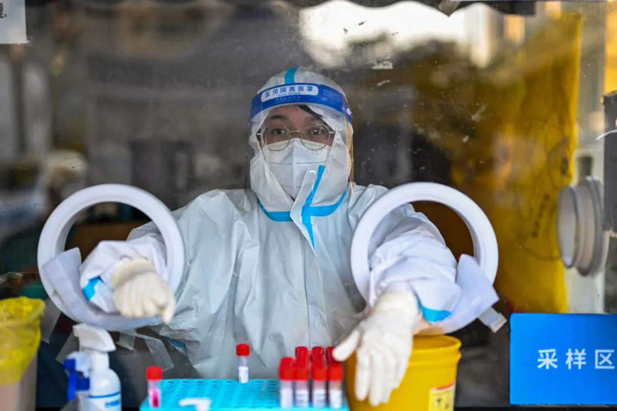 A health worker waits for people to take swab samples to test for COVID-19 in Shanghai on Dec. 19, 2022. (Hector Retamal/AFP via Getty Images)