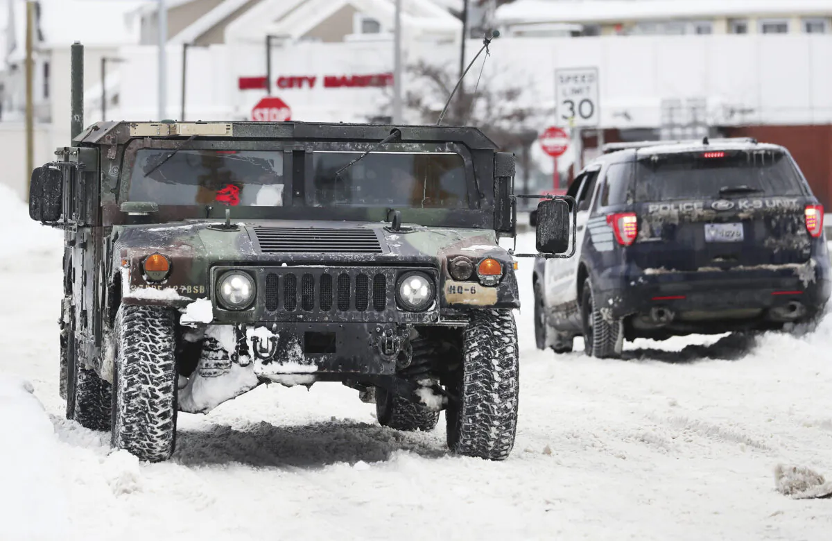 A National Guard truck drives past a police cruiser on a snowy street in Buffalo, N.Y., on Dec. 27, 2022. (Joseph Cooke/The Buffalo News via AP)