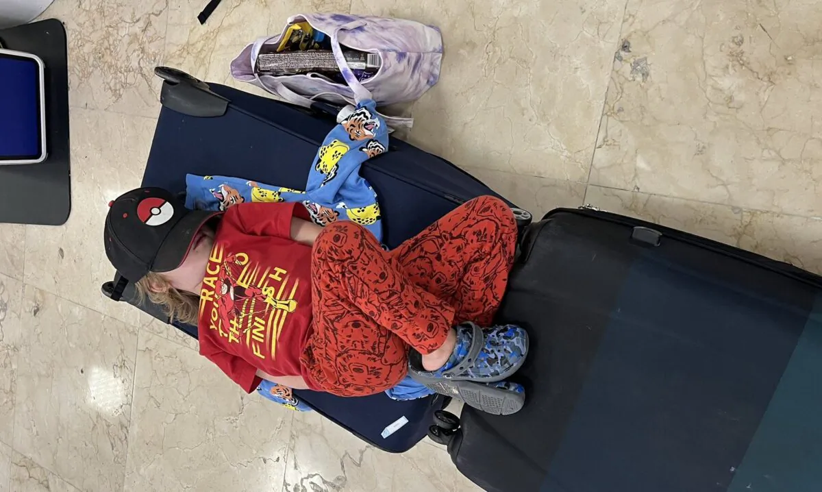 The 4-year-old son of Jared Ragel is asleep on a suitcase at the Cancun airport on Dec. 21, 2022, after delayed flights stranded hundreds of Canadians. (Courtesy of Jared Regel)