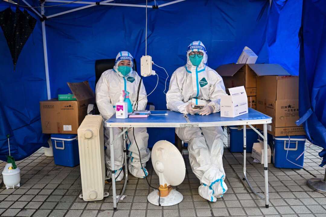 Health workers wait for people to scan a health code to test for COVID-19 in the Jing'an district in Shanghai, China, on Dec. 22, 2022. (Hector Retamal/AFP via Getty Images)