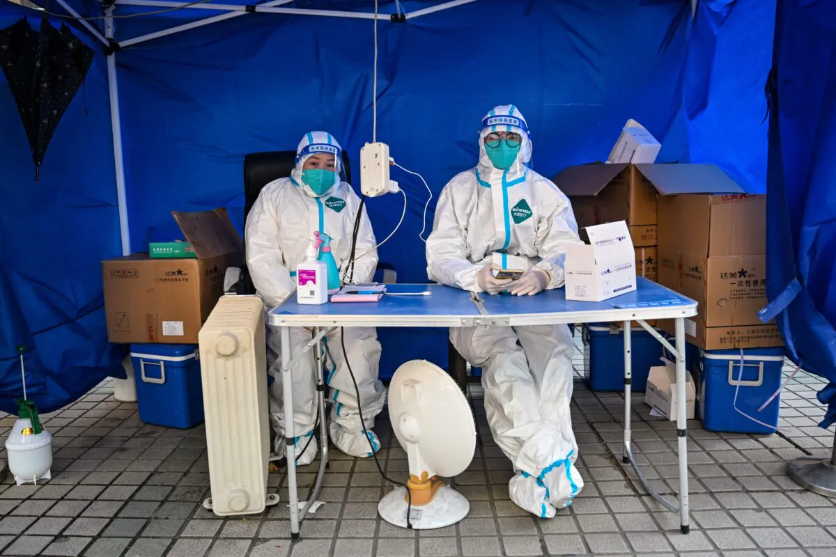 Health workers wait for people to scan a health code to test for the COVID-19 coronavirus in the Jing'an district in Shanghai, China, on Dec. 22., 2022. (Hector Retamal/AFP via Getty Images)