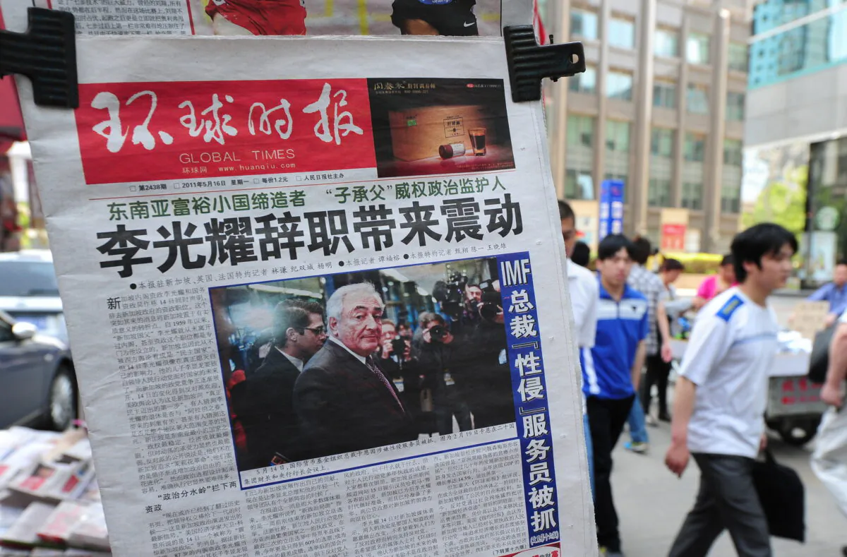 Pedestrians walk past a newsstand with the Chinese edition of the Global Times newspaper in Beijing on May 16, 2011. (Frederic J. Brown/AFP via Getty Images)