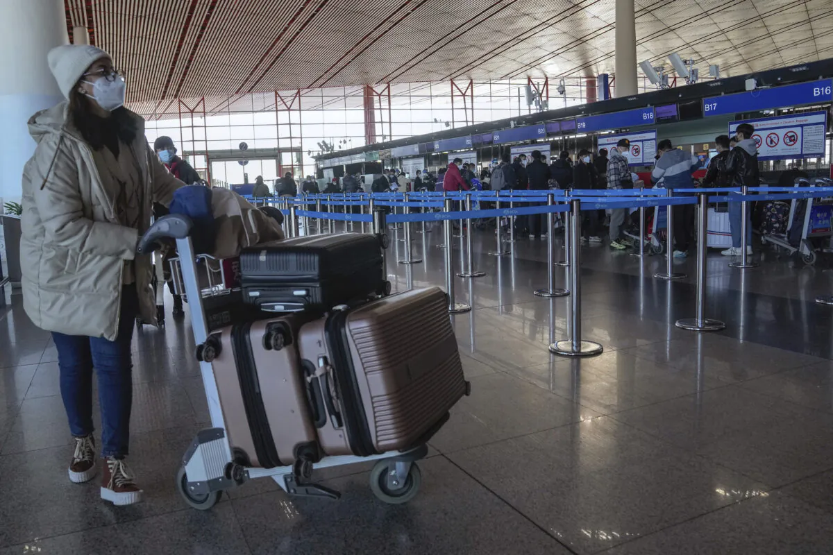 A masked traveler arrives at the international flight check in counter at the Beijing Capital International Airport in Beijing, on Dec. 29, 2022. (Andy Wong/AP Photo)