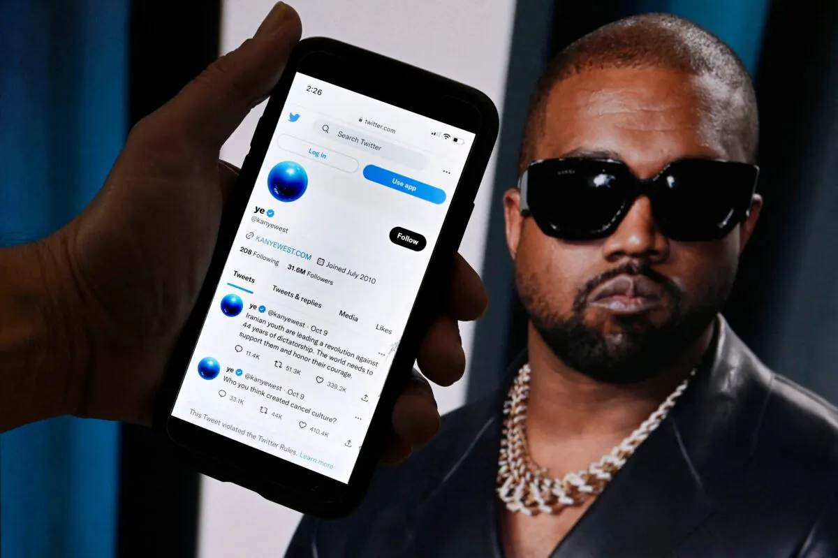 In this photo illustration, the Twitter account of Kanye West is displayed on a mobile phone with a photo of him shown in the background, in Washington, D.C., on Oct. 28, 2022. West’s Twitter account, which was temporarily locked out after posting anti-Semitic remarks, appeared to be back up on the platform, on Oct. 28 after billionaire Elon Musk took ownership of Twitter. (TNS)
