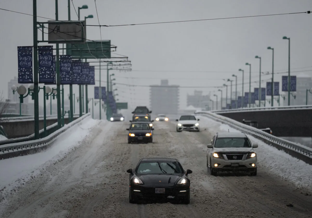 Motorists travel on the snow-covered Cambie Bridge as freezing rain falls in Vancouver, on Dec. 23, 2022. (Darryl Dyck/The Canadian Press)