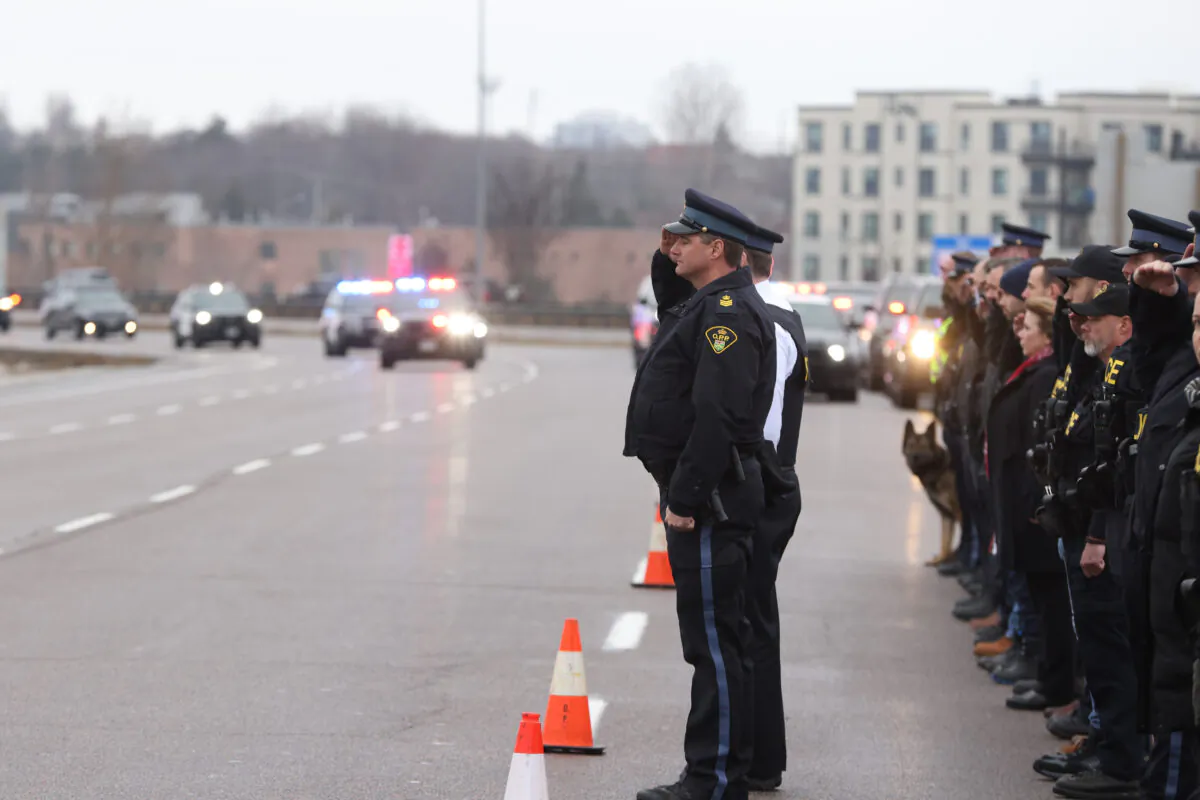 Members of the Ontario Provincial Police Orillia Detachment pay their respects as the hearse carrying Const. Grzegorz "Greg" Pierzchala arrives to the Duckworth exit in Barrie, Ontario, from Highway 400 on Dec. 30, 2022. (The Canadian Press/Christopher Drost)
