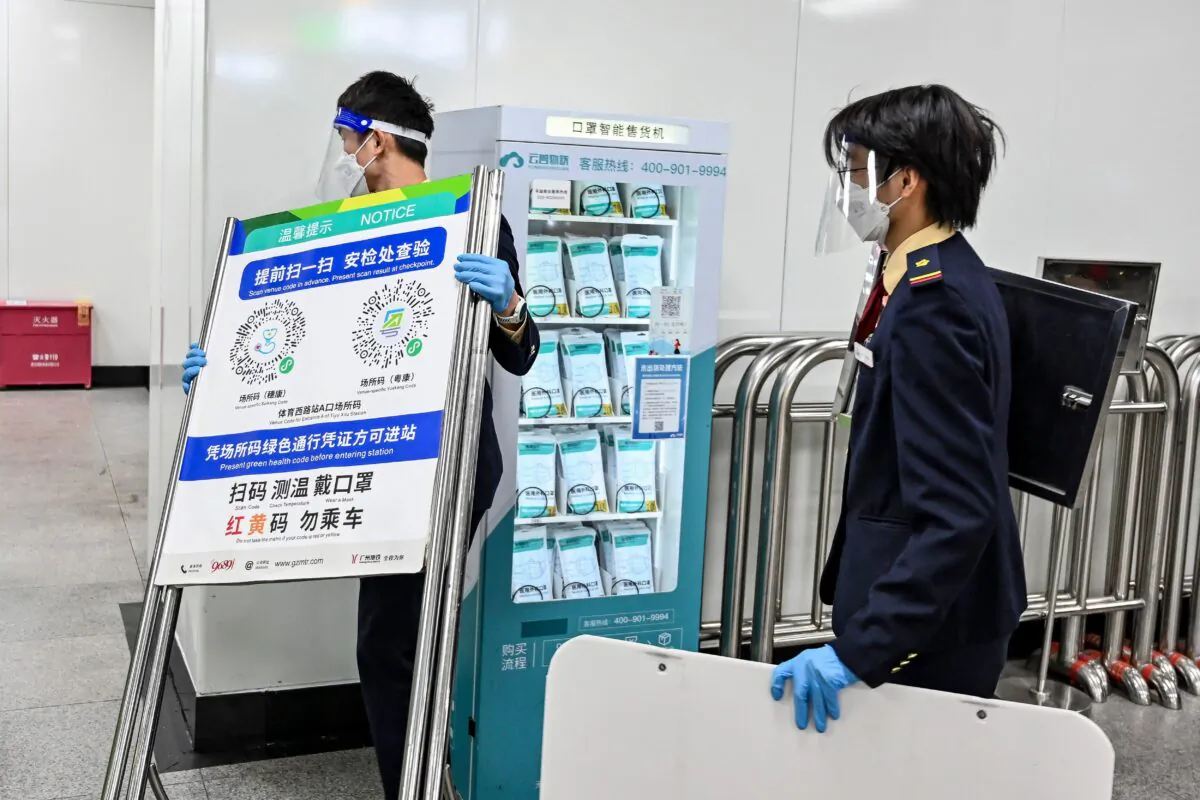 A subway staff member removes a poster for a COVID-19 health code used on entering the subway in Guangzhou, in China's southern Guangdong province, following the easing of COVID-19 restrictions on Dec. 7, 2022. (CNS/AFP via Getty Images)