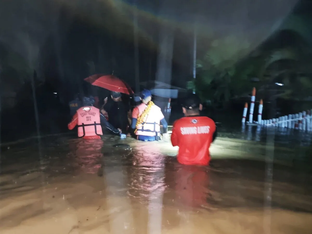 Members of the Philippine Coast Guard wade through a flooded street during a rescue operation, in Isabela, Basilan Province, Philippines, on Dec. 27, 2022. (Philippine Coast Guard/Handout via Reuters)