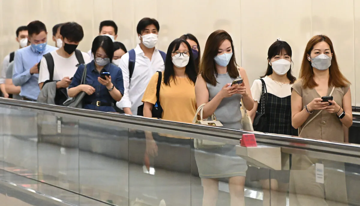 The Department of Health published the first part of the Report of Population Health Survey 2020-22. The survey was conducted between November 2020 and January 2022, showing that a quarter of Hong Kong adults have insufficient physical activity. The picture shows Hongkongers studying their cell phones while on their way to take the trains, on Aug. 25, 2022. (Sung Pi-Lung/The Epoch Times)