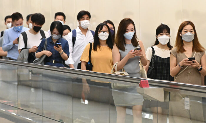 The Department of Health published the first part of the Report of Population Health Survey 2020-22. The survey was conducted between November 2020 and January 2022, showing that a quarter of Hong Kong adults have insufficient physical activity. The picture shows Hongkongers studying their cell phones while on their way to take the trains, on Aug. 25, 2022. (Sung Pi-Lung/The Epoch Times)