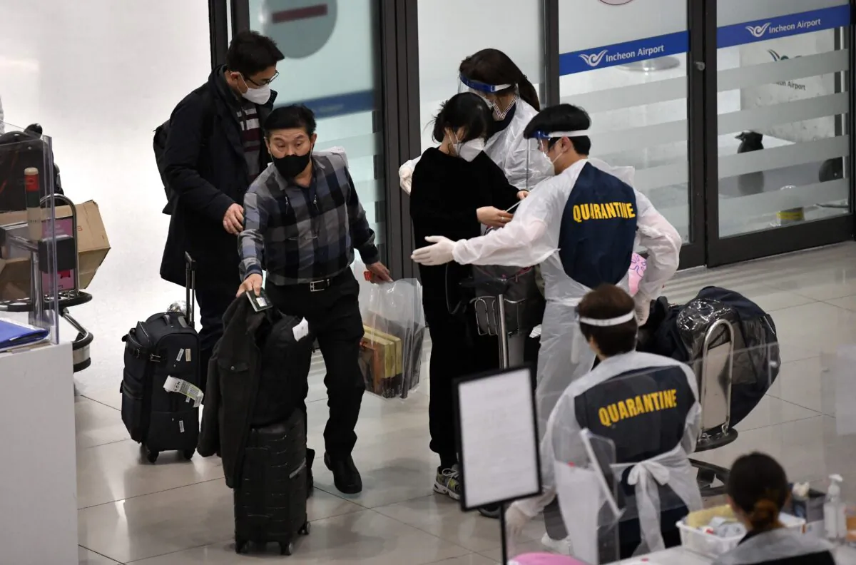 Staff members wearing protective equipment guide travellers at the arrival hall of Incheon International Airport in South Korea, on Nov. 30, 2021. (Jung Yeon-je /AFP via Getty Images)