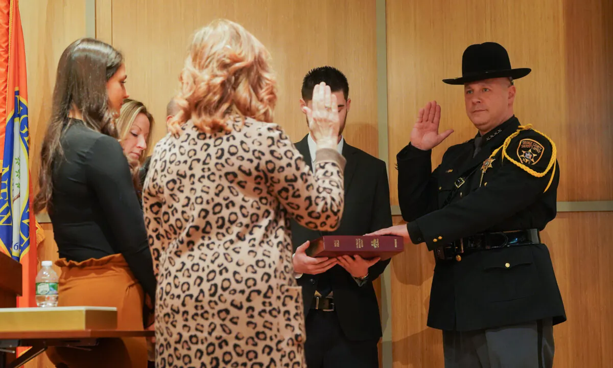 Paul Arteta (R) takes oath with his left hand on his mother's Bible to become the new sheriff of Orange County, New York, on Jan. 1, 2023. (Cara Ding/The Epoch Times)