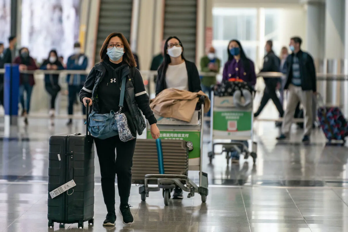 Travellers walk with their luggage at the arrival hall of the Hong Kong International Airport on Dec. 30, 2022. (Anthony Kwan/Getty Images)