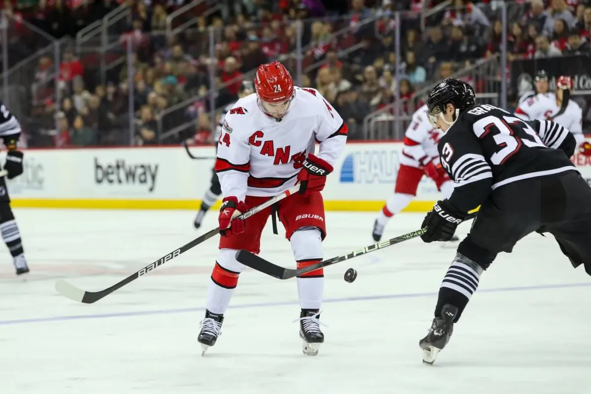 Carolina Hurricanes center Seth Jarvis (24) and New Jersey Devils defenseman Ryan Graves (33) look to control the puck during the first period at Prudential Center in Newark, N.J., on Jan. 1, 2023. (Thomas Salus/USA TODAY Sports via Field Level Media)