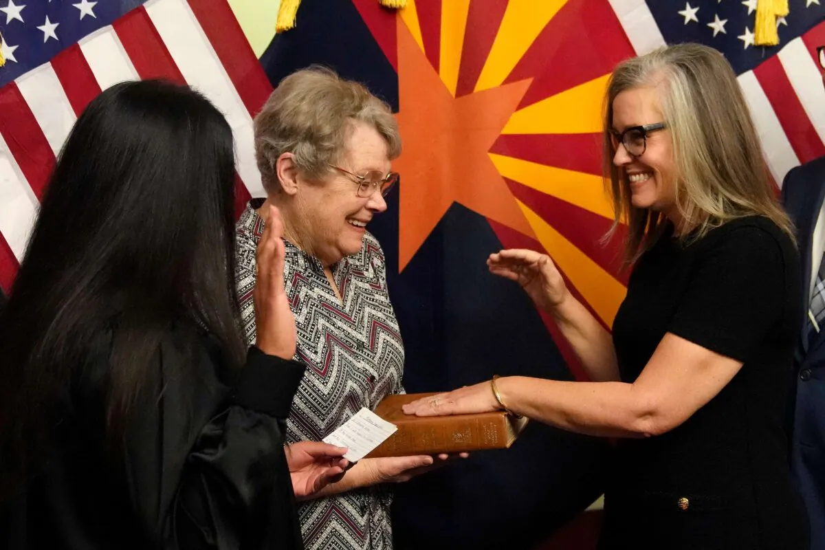 Arizona Democrat Gov. Katie Hobbs (R) pauses during taking the oath of office in a ceremony as she laughs with her mother Linda Hobbs, as U.S. Circuit Judge for the Ninth Circuit Court of Appeals Roopali Desai (L) administers the oath at the state Capitol in Phoenix, on Jan. 2, 2023. (Ross D. Franklin, Pool/AP Photo)
