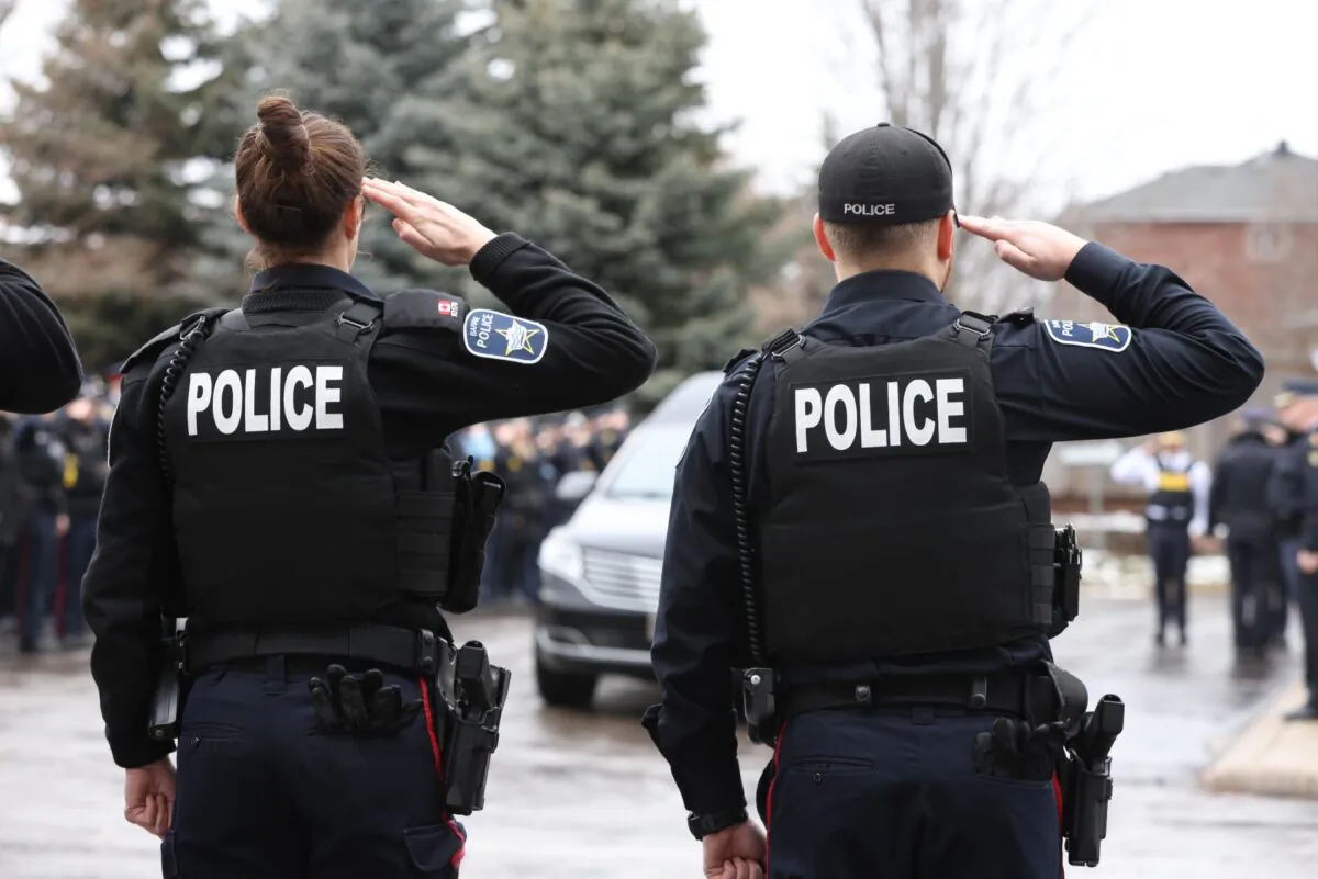 Barrie Police salute as the hearse carrying OPP Const. Grzegorz "Greg" Pierzchala arrives at Adams Funeral Home in Barrie, Ont., Friday, Dec. 30, 2022. (Christopher Drost/The Canadian Press)