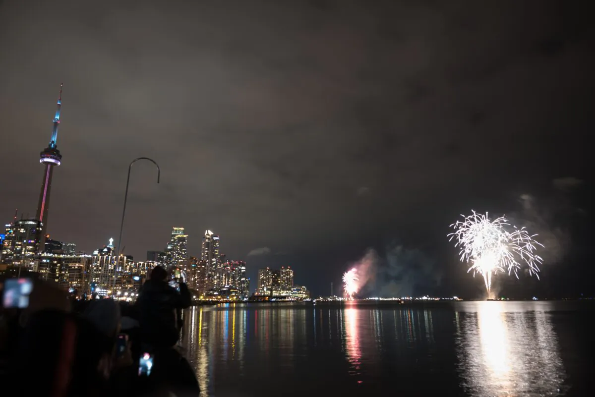 People watch the New Year's fireworks display over Toronto's inner harbour just after midnight from Ireland Park, on Jan. 1, 2023.  (The Canadian Press/Tijana Martin)