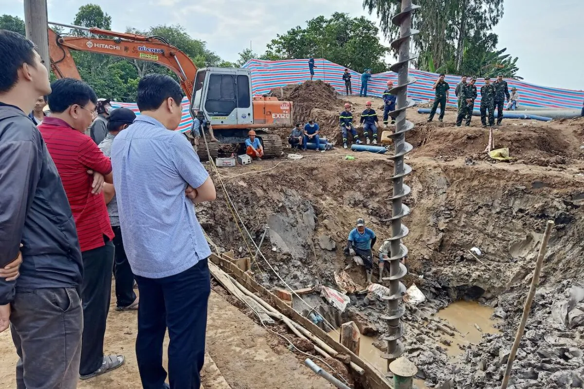 Rescuers look down into the site of where a 10-year-old boy is thought to be trapped in a 35-meter deep shaft at a bridge construction area in Vietnam's Dong Thap province, on Jan. 2, 2023. (STR/AFP via Getty Images)