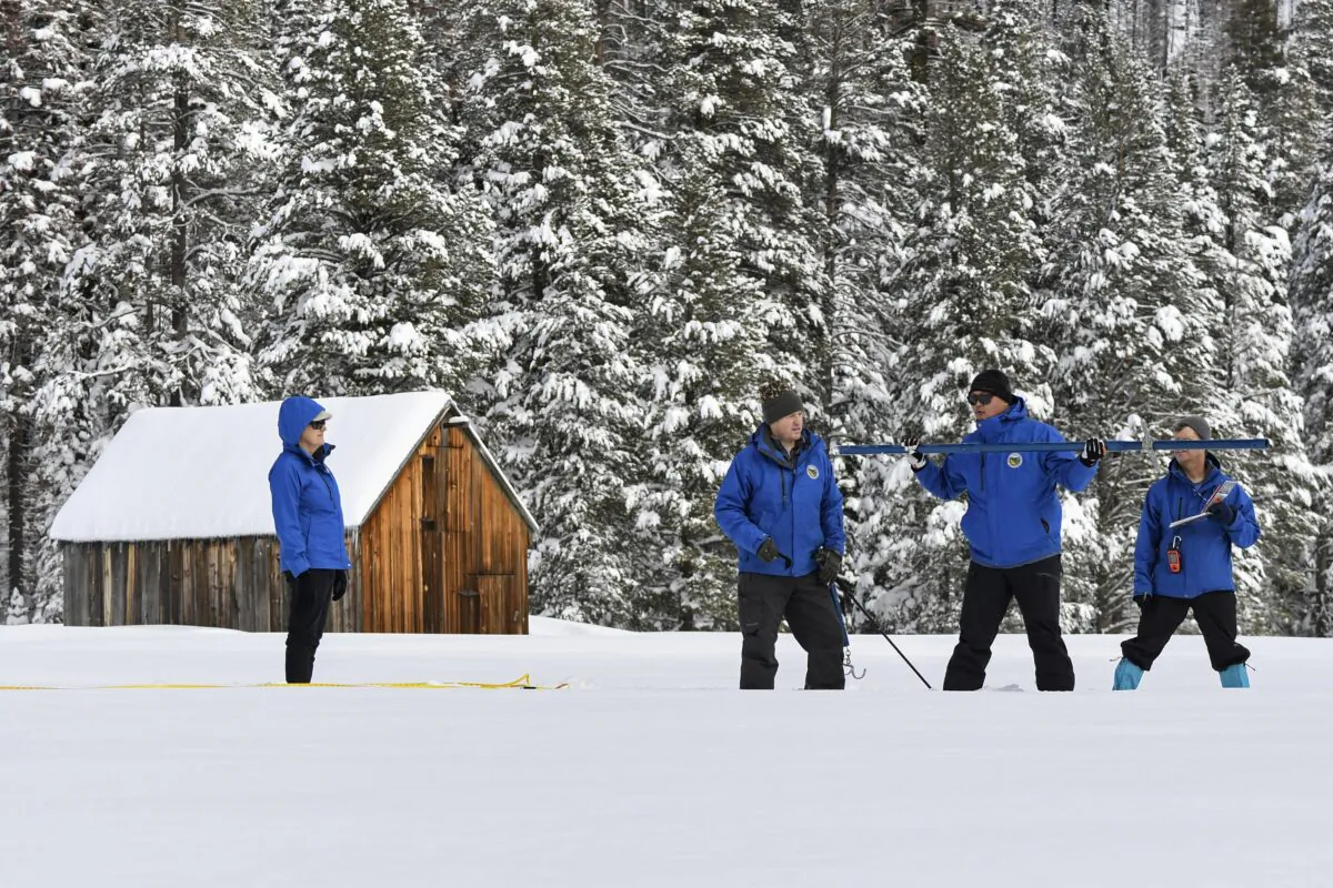In this photo provided by the California Department of Water Resources, forecasting chief Sean de Guzman, second from right, and engineers work the measurement phase of the first media snow survey of the season at Phillips Station in the Sierra Nevada Mountains, Calif., on Jan. 3, 2023. (Kenneth James/California Department of Water Resources via AP)