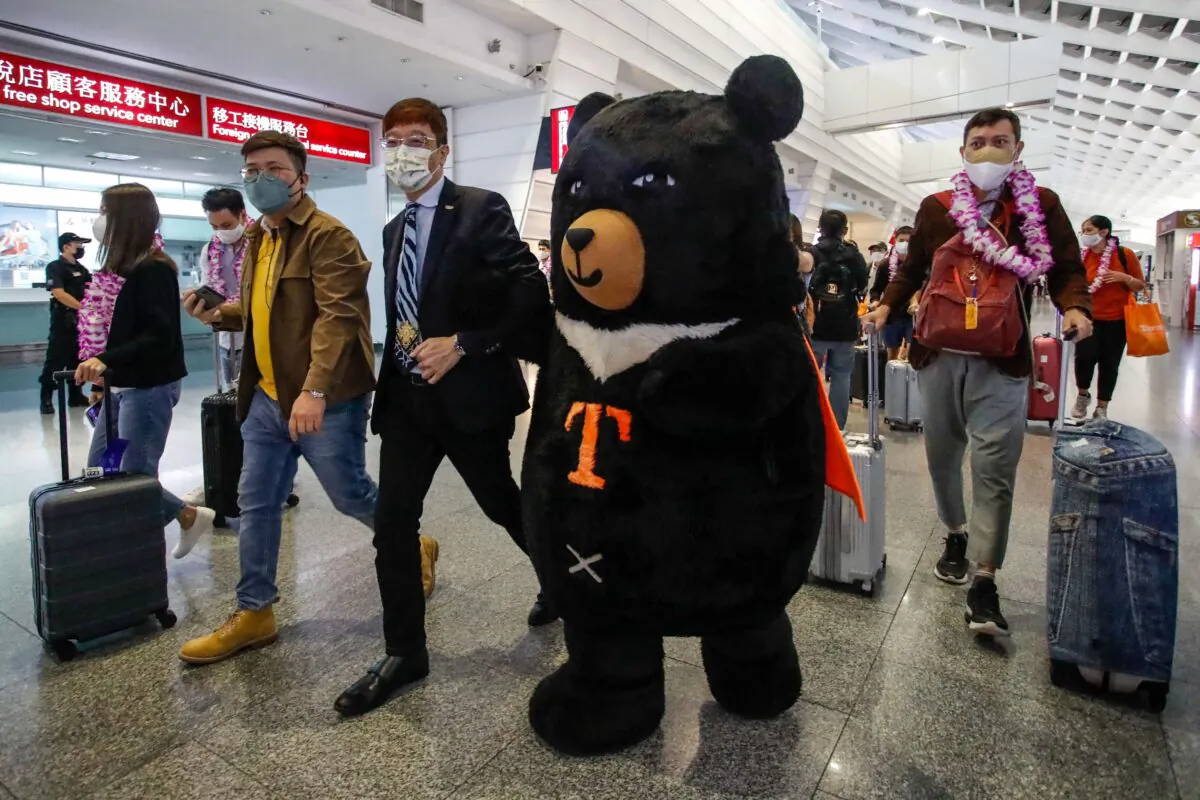 A mascot and an official welcome a group of passengers from Thailand at Taoyuan International Airport in Taoyuan on October 13, 2022, after Taiwan reopened its borders by ending mandatory Covid quarantine for arrivals. (Daniel Ceng/AFP via Getty Images)