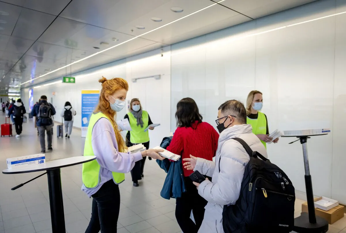 An employee of the the Dutch Municipal Health Service (GGD) hands out free COVID-19 self-test kits to travelers arriving from China, at Schiphol Airport, Netherlands, on Jan. 4, 2023. (Robin van Lonkhuijsen/ANP/AFP via Getty Images)