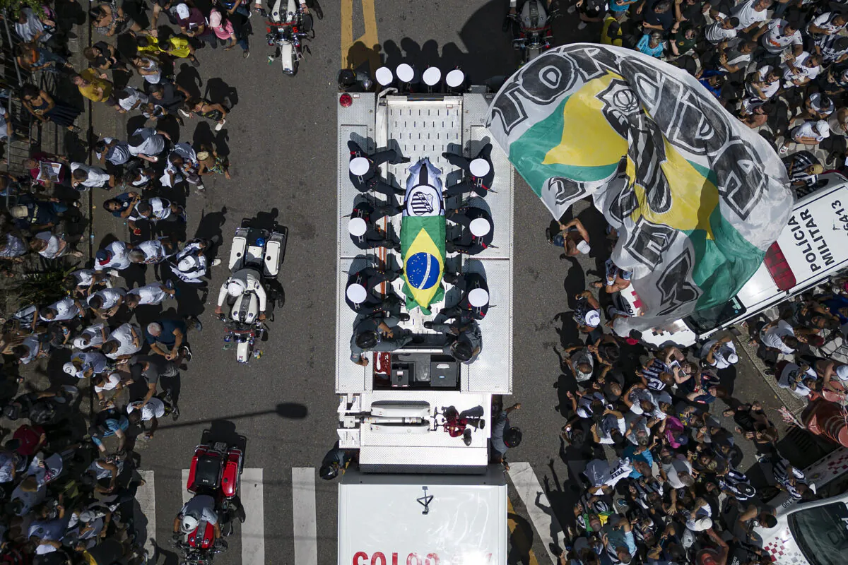 The casket of late Brazilian soccer great Pele is draped in the Brazilian and Santos FC soccer club flags as his remains are transported from Vila Belmiro stadium, where he laid in state, to the cemetery during his funeral procession in Santos, Brazil, on Jan. 3, 2023. (Matias Delacroix/AP Photo)