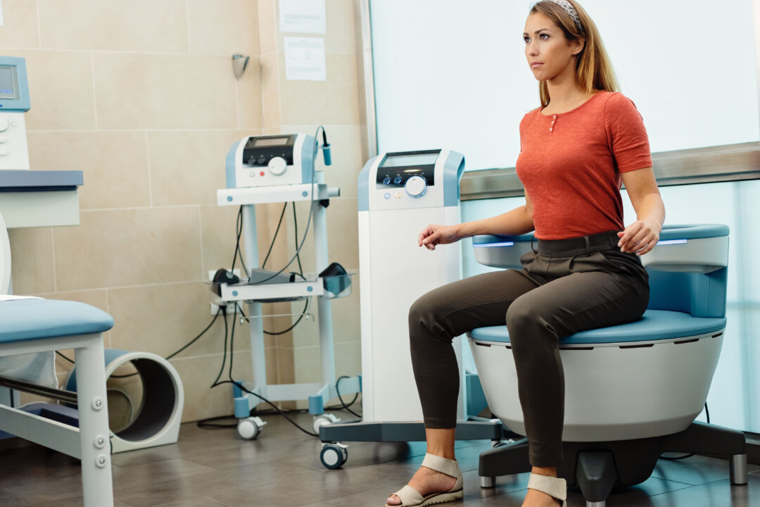 Young woman sitting in treatment chair while restoring neuromuscular control for urinary incontinence at medical clinic. (Shutterstock)