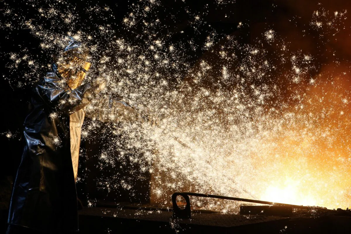 A steel worker of ThyssenKrupp stands amid sparks of raw iron coming from a blast furnace at a ThyssenKrupp steel factory in Duisburg, Germany, on Nov. 14, 2022. (Wolfgang Rattay/Reuters)