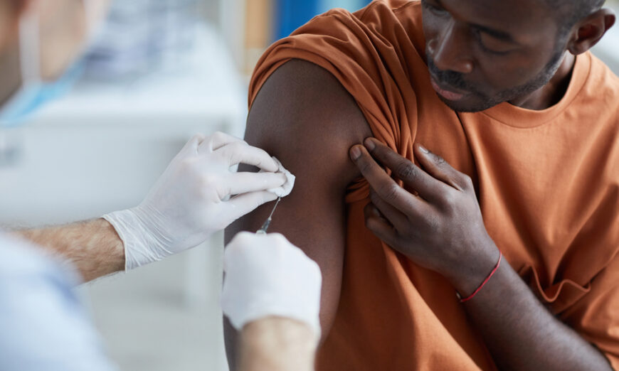 A nurse injects a vaccine in the shoulder of an African-American man. (Shutterstock)