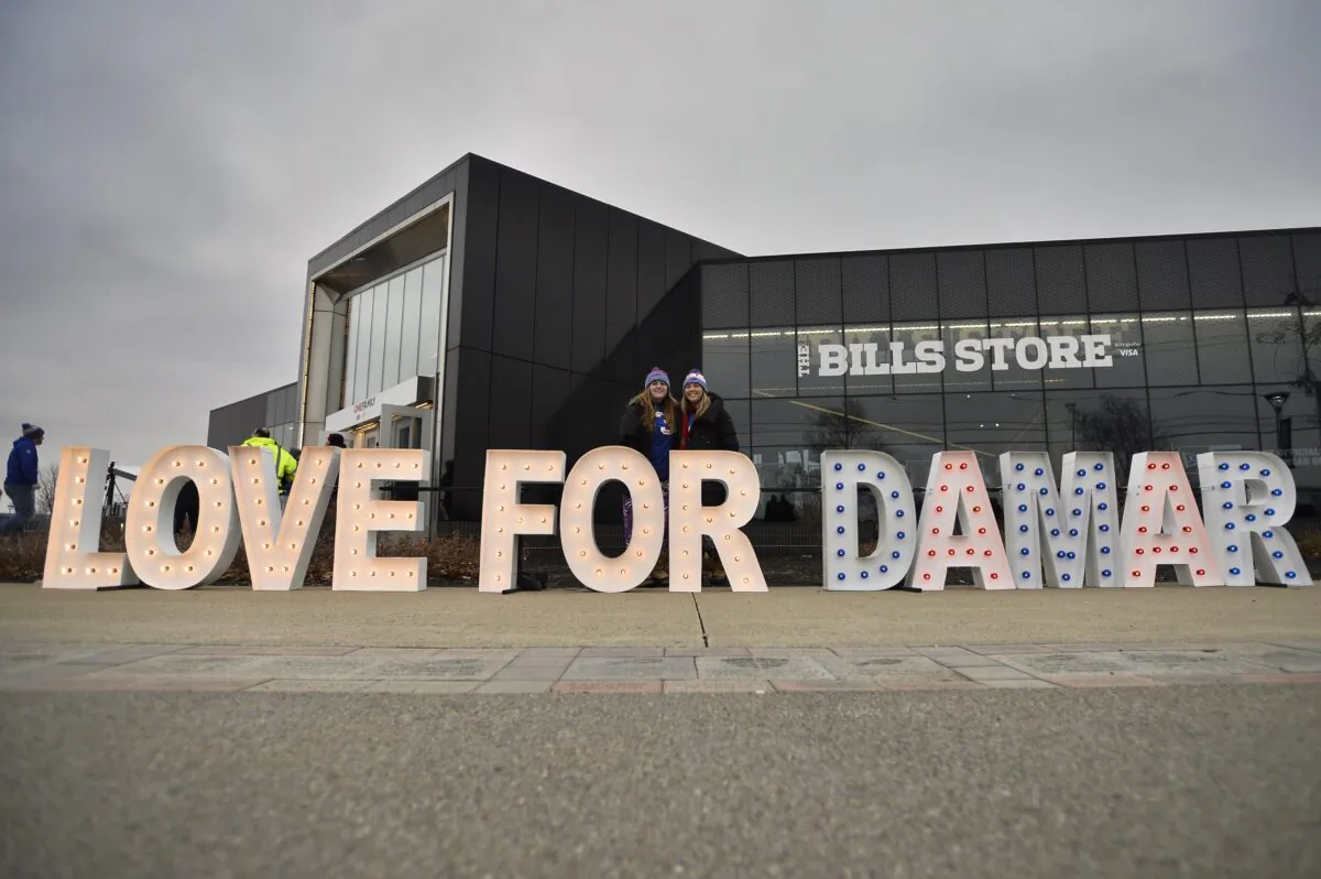 Fans stand for photographs by a sign in support of Buffalo Bills safety Damar Hamlin outside Highmark Stadium before an NFL football game against the New England Patriots in Orchard Park, N.Y., on Jan. 8, 2023. (Adrian Kraus/AP Photo)