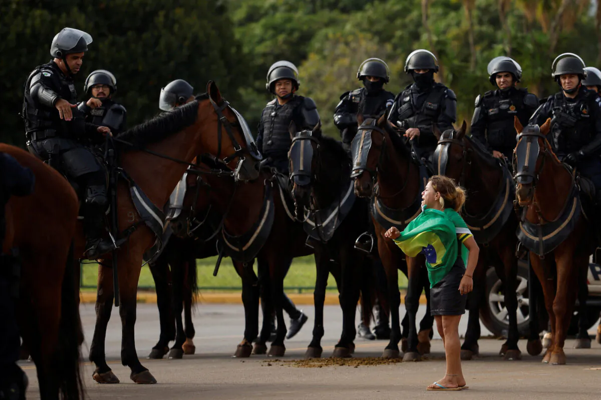 A demonstrator reacts next to members of security forces as supporters of Brazil's former President Jair Bolsonaro leave a camp outside the Army Headquarters, in Brasilia, Brazil, on Jan. 9, 2023. (Amanda Perobelli/Reuters)