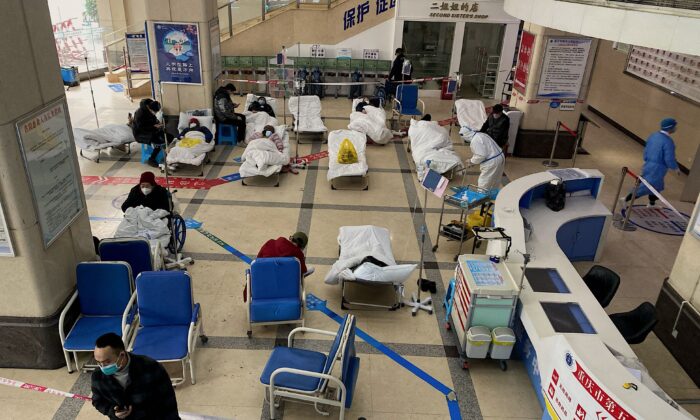 A man stands in front of a cordoned-off area, where COVID-19 patients lie on hospital beds in the lobby of the Chongqing No. 5 People's Hospital in China's southwestern city of Chongqing on Dec. 23, 2022. (AFP via Getty Images)