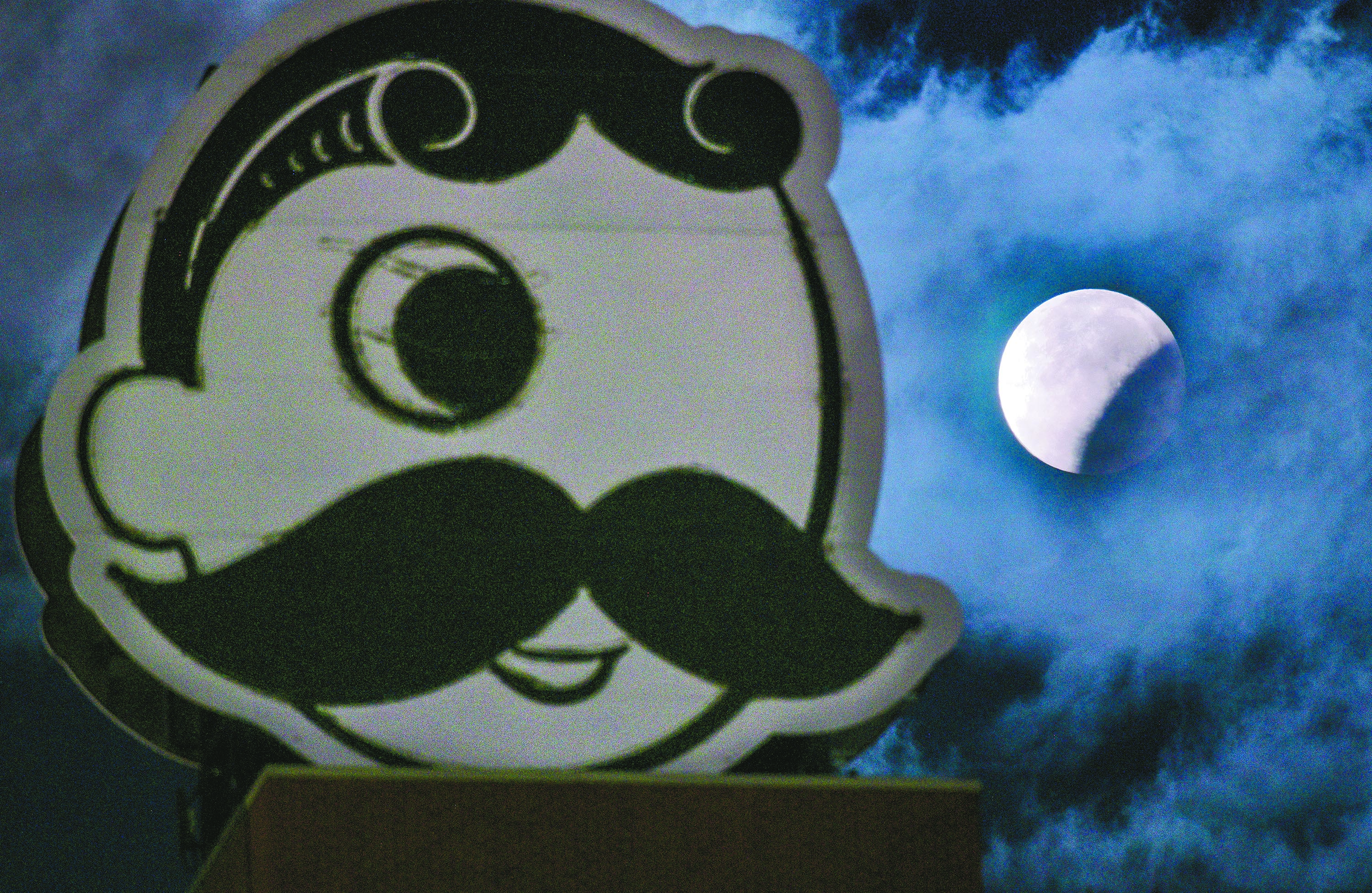 The full beaver moon is seen in partial eclipse beyond an unlit Natty Boh on Baltimore's Brewers Hill in November 2021. 