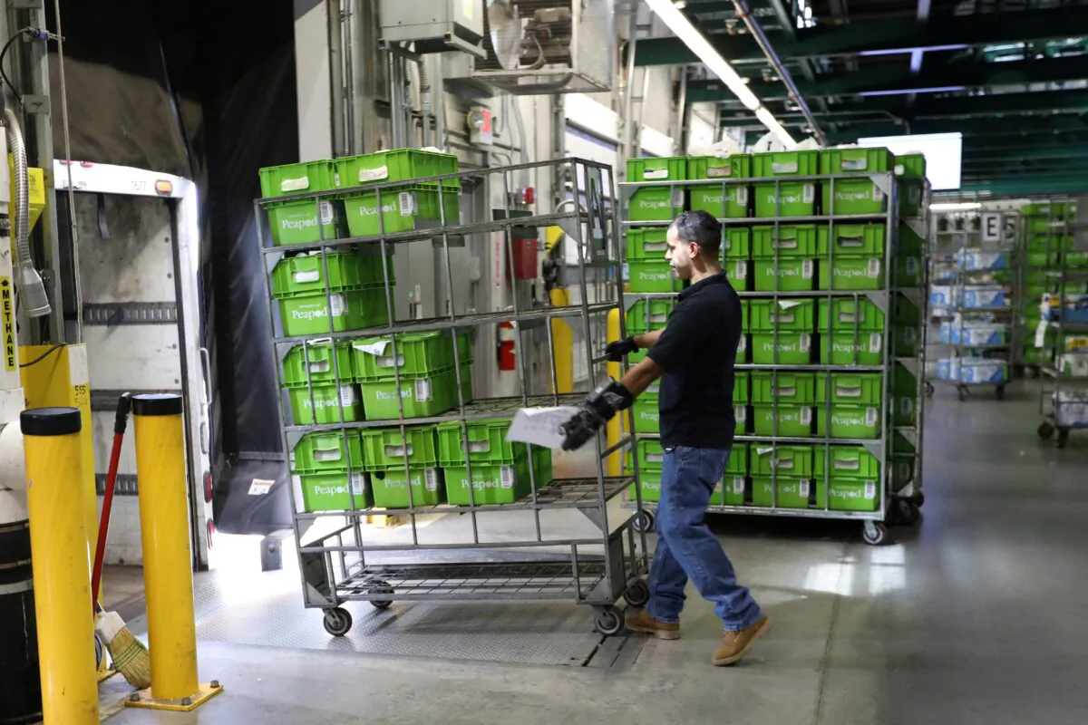 A delivery worker loads trucks with totes packed with groceries for delivery inside a Peapod grocery distribution warehouse facility in Jersey City, N.J., on Aug. 21, 2018. (Mike Segar/Reuters)