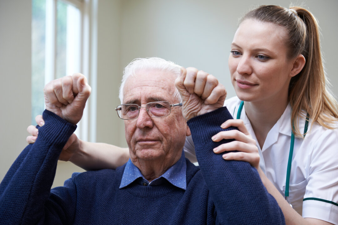 Nurse Assessing Stroke Victim By Raising Arms. (Shutterstock)