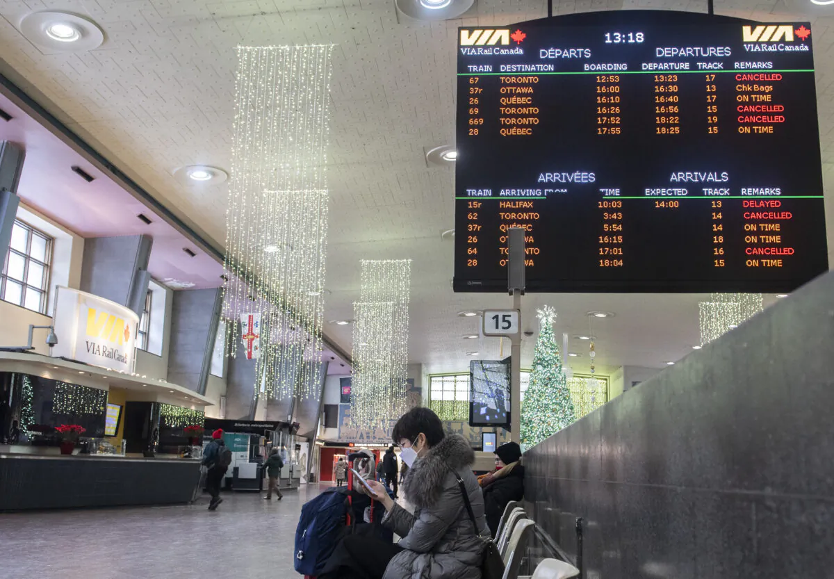 A woman beneath a Via Rail schedule board at central station in Montreal on Dec. 26, 2022. A Christmas Eve train derailment is also continuing to wreak havoc on holiday travel plans in Ontario and Quebec. (The Canadian Press/Graham Hughes)