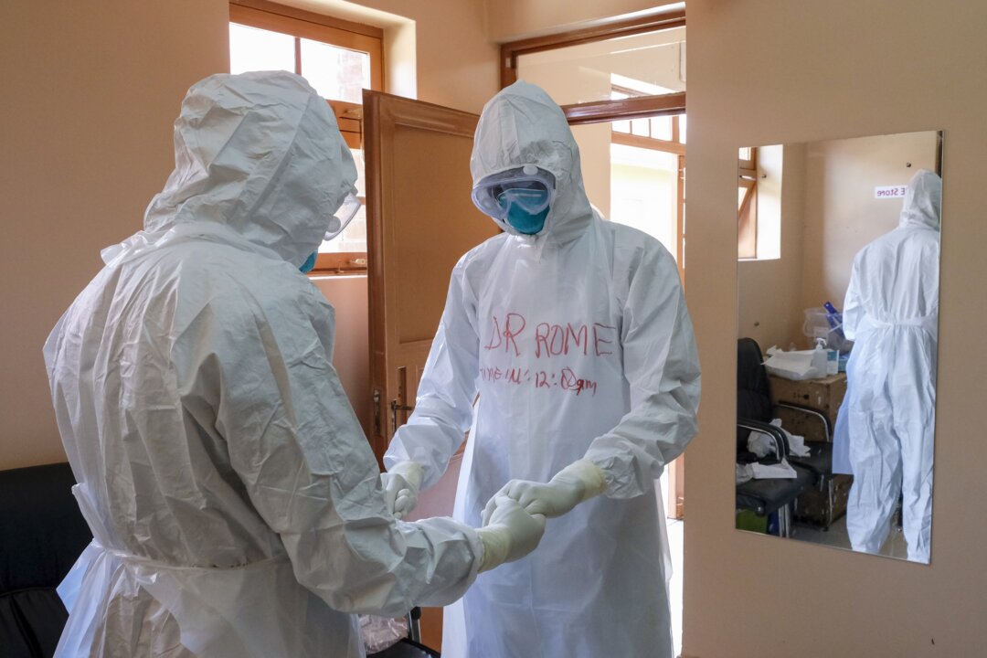 Doctors wearing protective equipment pray together before they visit a patient who was in contact with an Ebola victim, in the isolation section of Entebbe Regional Referral Hospital in Entebbe, Uganda, on Oct. 20, 2022. (Hajarah Nalwadda/AP Photo)