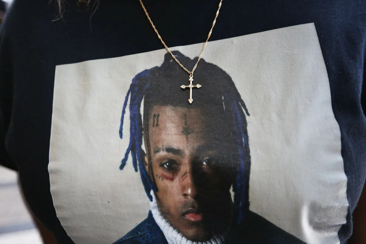 A fan wears a cross around her neck dangling on a t-shirt in remembrance before she enters a memorial for rapper XXXTentacion in Sunrise, Fla., on June 27, 2018. (Brynn Anderson/AP Photo)