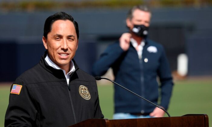 California Governor Gavin Newsom (back) listens as San Diego Mayor Todd Gloria speaks to members of the media during a press conference at Petco Park in San Diego, Calif., on Feb. 8, 2021. (Sandy Huffaker/AFP via Getty Images)