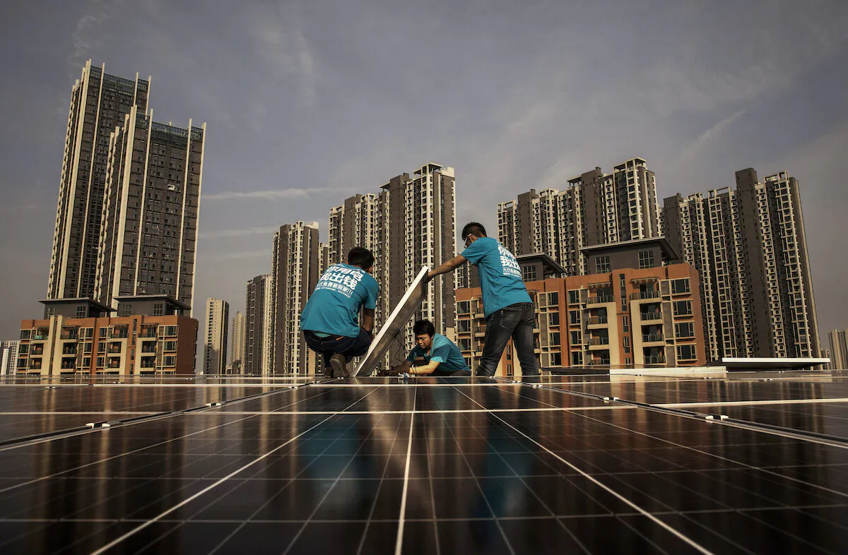 Chinese workers from Wuhan Guangsheng Photovoltaic Company install solar panels on the roof of a building on April 27, 2017 in Wuhan, China. (Kevin Frayer/Getty Images)