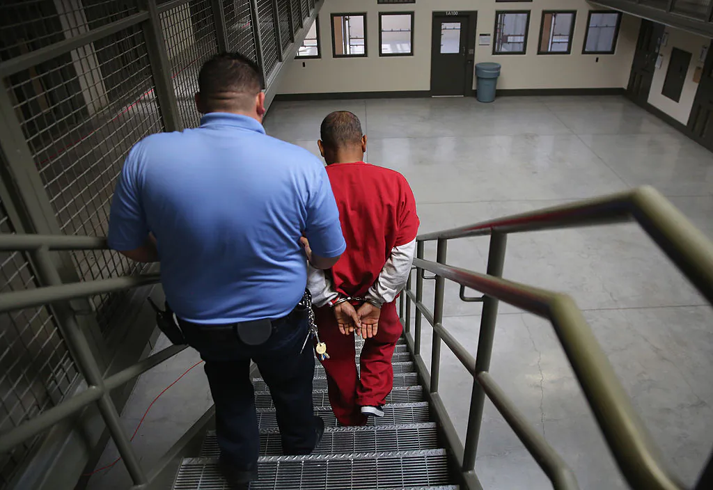 A guard escorts an immigrant detainee from his 'segregation cell' back into the general population at the Adelanto Detention Facility in Adelanto, Calif., on Nov. 15, 2013. (John Moore/Getty Images)