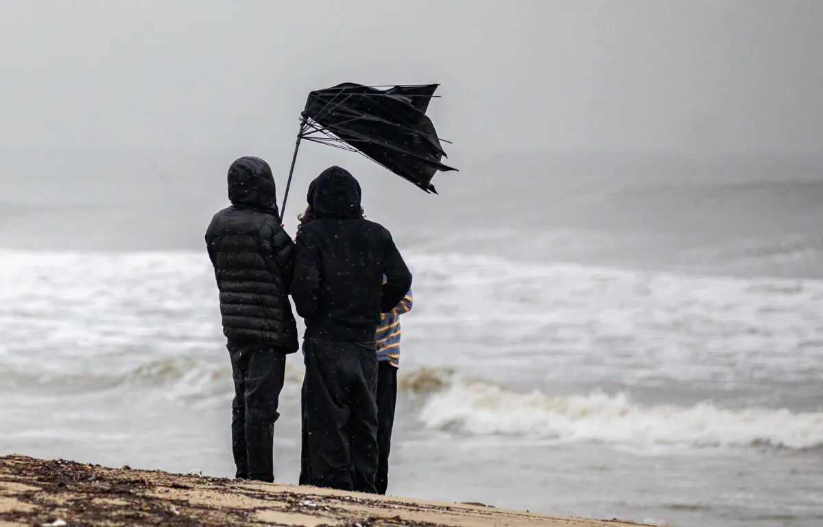 Teenagers try to grip their umbrella though high winds in Santa Monica, Calif., on Jan. 14, 2023. (John Fredricks/The Epoch Times)