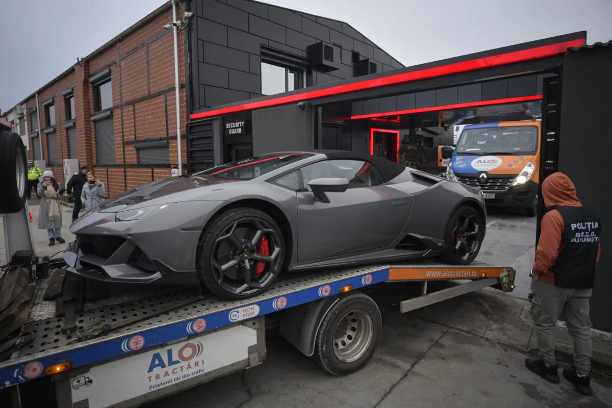 A police officer looks on as a luxury vehicle which was seized in a case against media influencer Andrew Tate, is towed away, on the outskirts of Bucharest, Romania, on Jan. 14, 2023. (Alexandru Dobre/AP Photo)