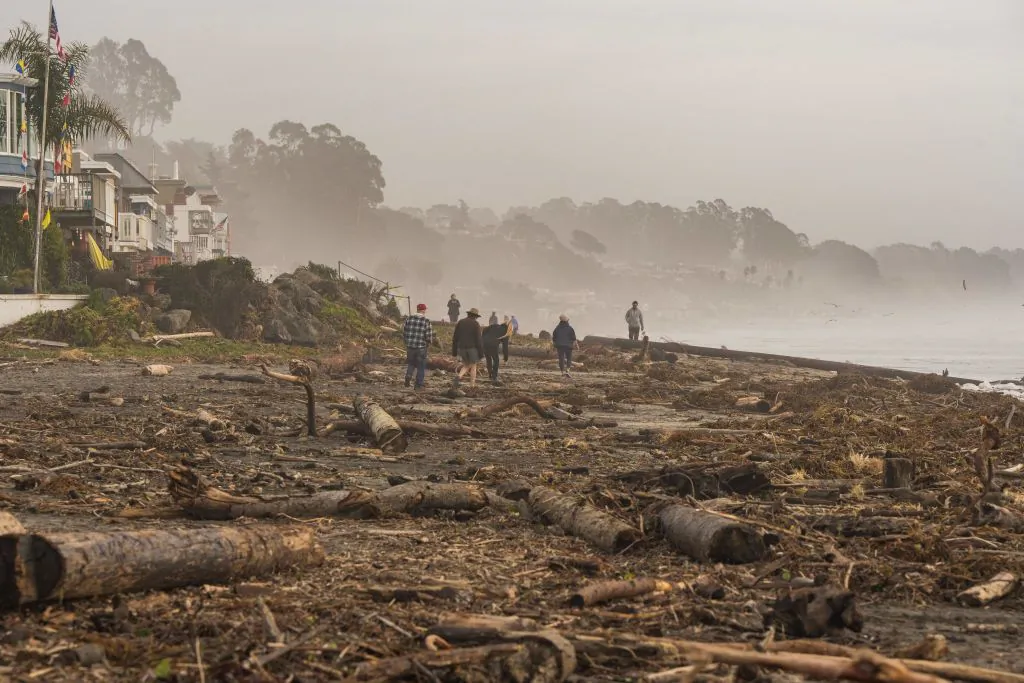 TOPSHOT - People walk on Rio Del Mar beach, covered with storm debris, in Aptos, California on January 12, 2023.  (Nic Coury/AFP/Getty Images)