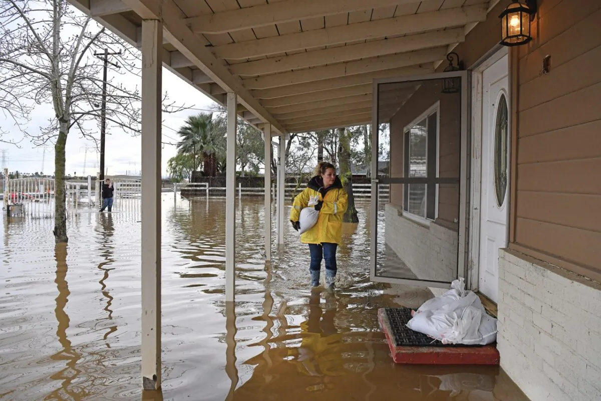 Stephanie Beard, of Brentwood, carries a sand bag to her flooded home on Bixler Road in Brentwood, Calif., on Jan. 16, 2023. (Jose Carlos Fajardo/Bay Area News Group via AP)