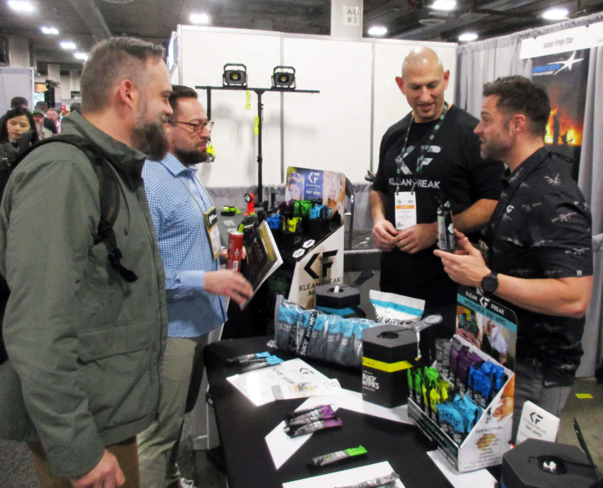 (Right) Tim Goalen (owner of Klean Freak) and (Center) Carlos Nunio demonstrate their product to (Center left) Landon Bench and (Left) Grant Cottrell (both of Bentonville, Ark.) during SHOT Show in Las Vegas, Nev., on Jan. 17, 2023. (Michael Clements)