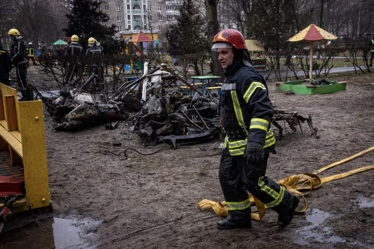 Firemen roll up hoses in front of debris as emergency service workers respond at the site of a helicopter crash in Brovary, Ukraine, on Jan. 18, 2023. (Ed Ram/Getty Images)