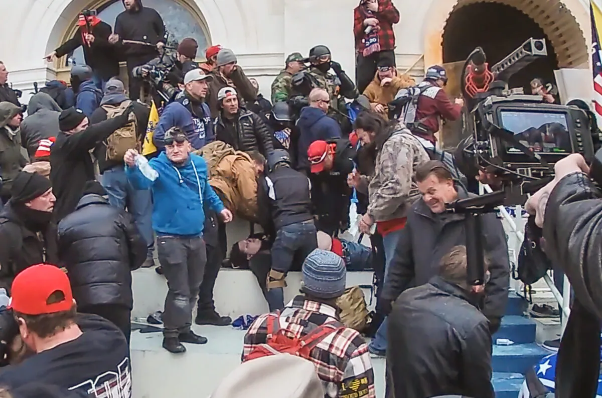 Ronald McAbee (in the red cap at center) leans over a prone Rosanne Boyland as another protester does CPR on the lifeless woman on Jan. 6, 2021. (Special to The Epoch Times)